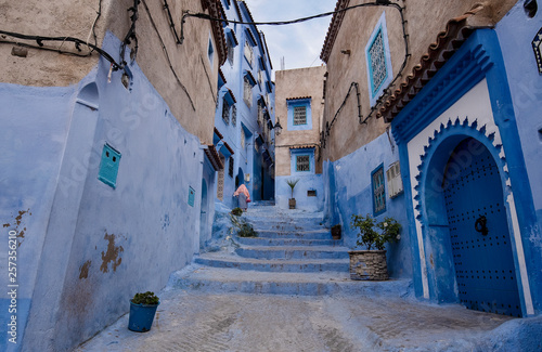 Beautiful view of the blue city in the medina of CHEFCHAOUEN, MOROCCO. Traditional moroccan architectural details and painted houses. street with flowers and bright blue walls with arch © mitzo_bs