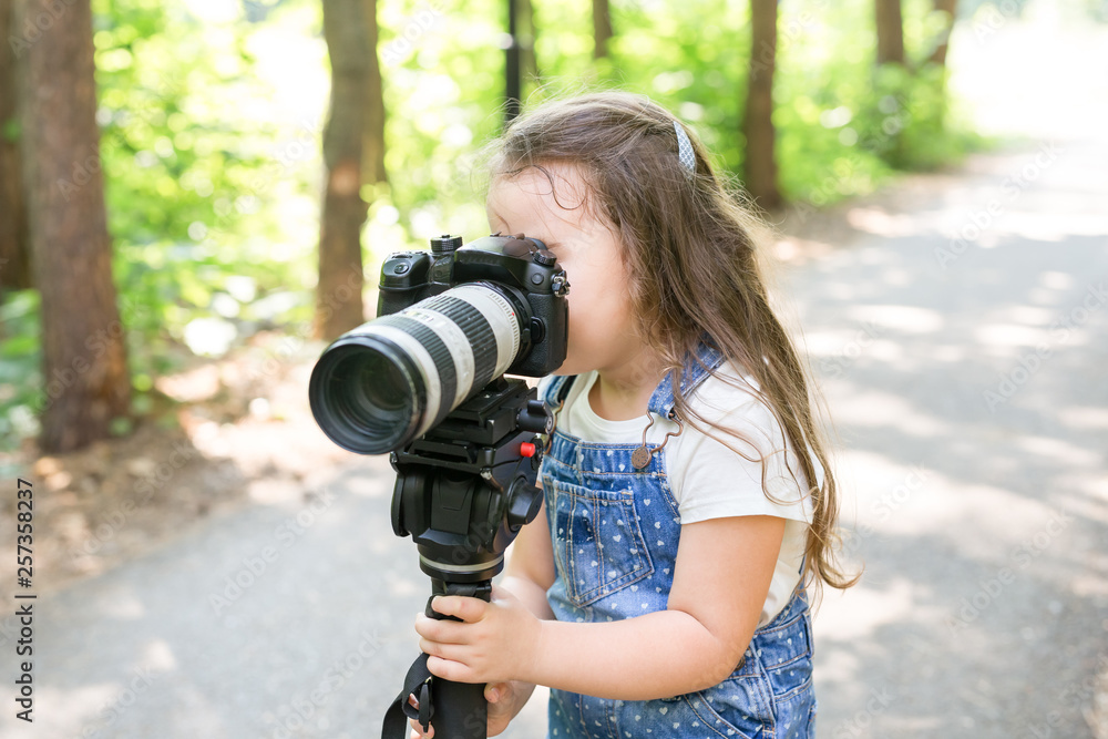 Hobby, profession, children and photographer concept - child with camera in forest Hobby, profession, children and photographer concept - child with camera in forest