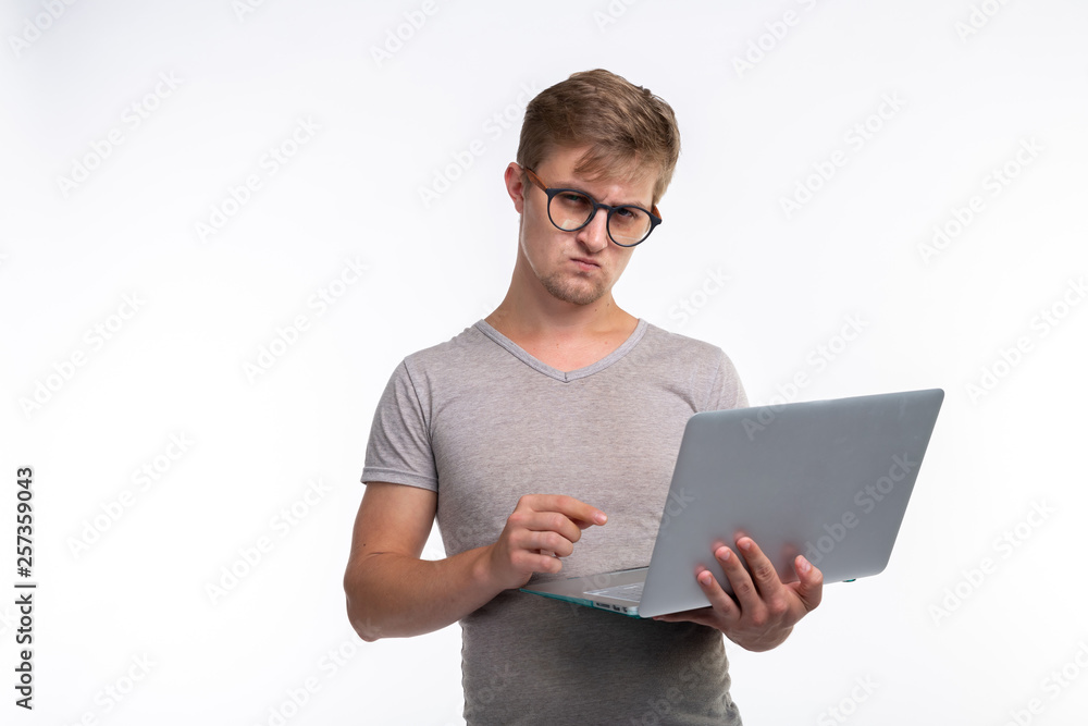 Study, education and people concept - a serious young handsome man look at netbook on white background Study, education and people concept - a serious young handsome man look at netbook on white background