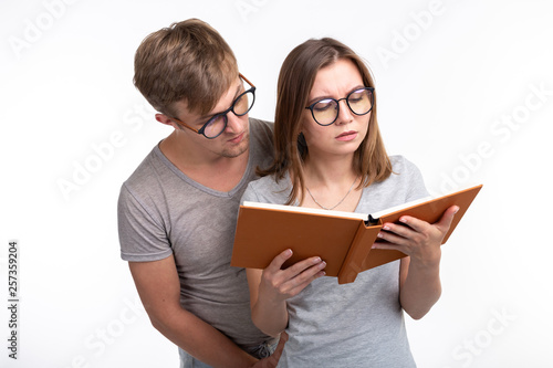 Studying together and people concept - a couple of young people reading a book