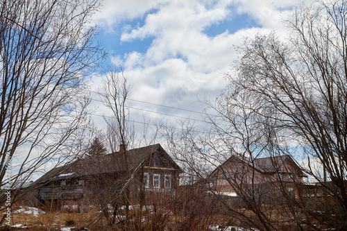 Old houses in the abandoned small village, branch of trees and sky with clouds background © keleny