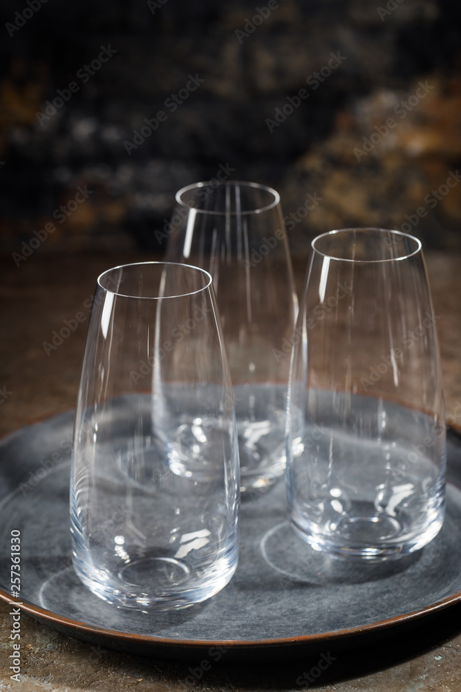Empty transparent glasses on tray over stone background Empty transparent glasses on tray over stone background