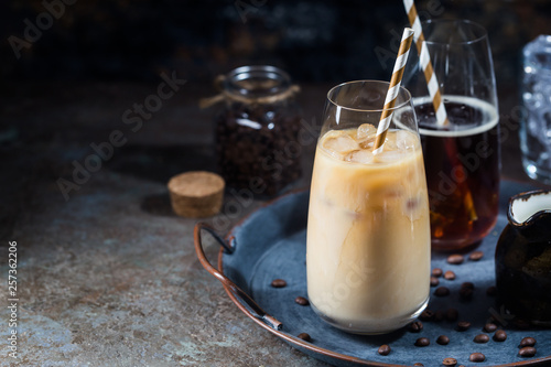 Ice coffee cold summer drink in a tall glass and coffee beans on a stone background.