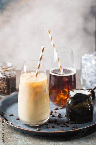 Ice coffee cold summer drink in a tall glass and coffee beans on a stone background.