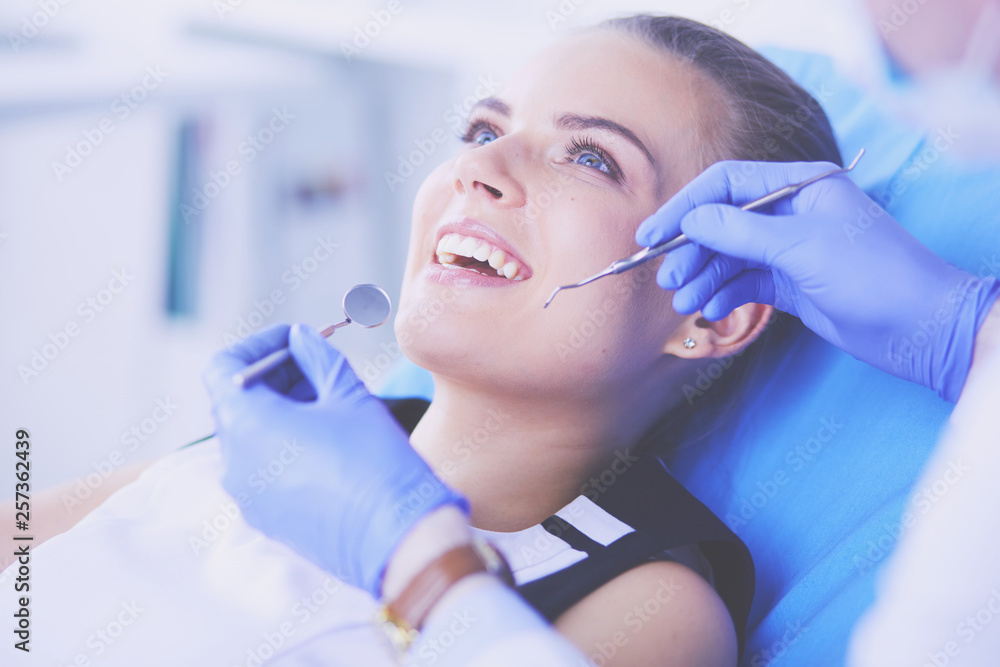 Fototapeta premium Young Female patient with open mouth examining dental inspection at dentist office.