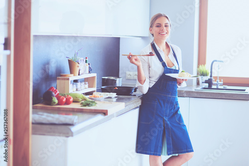 Young woman standing by the stove in the kitchen