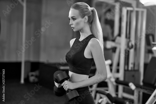 Athletic, active girl working out with dumbbells in gym.