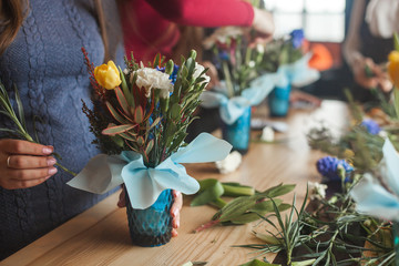 Women on the master-class on floristics. Young ladies making floral composition. Group of females with flowers indoor at the loft background. Decoration process.