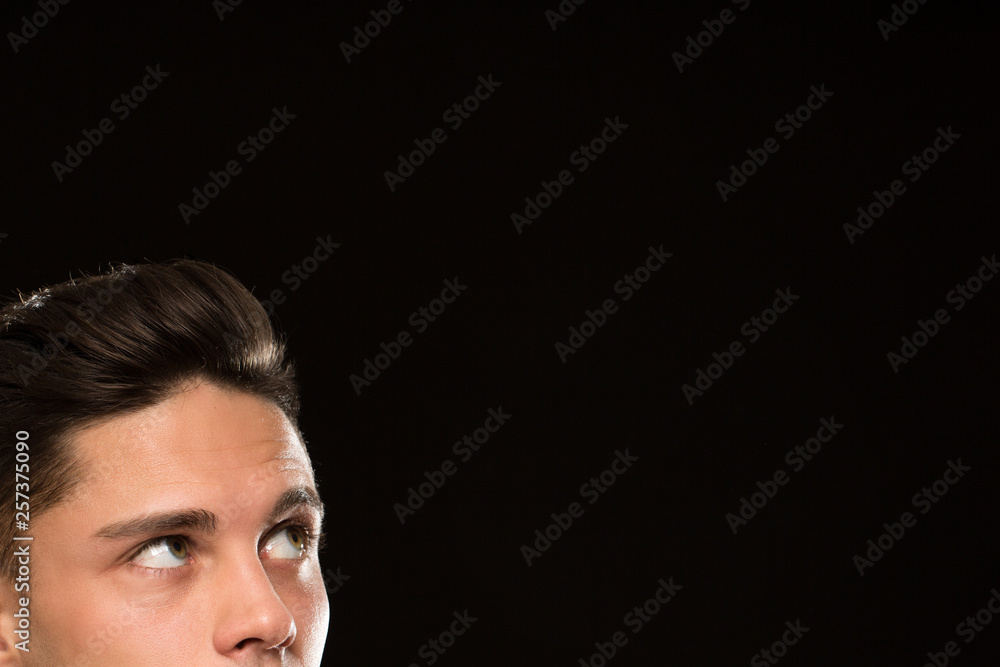Cropped close up of a handsome young man with classy hairstyle looking at the copyspace on black background eyes half face emotions news ads expressive barbershop barber Cropped close up of a handsome young man with classy hairstyle looking at the copyspace on black background eyes half face emotions news ads expressive barbershop barber