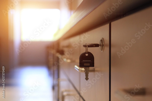Close up key locked on filing cabinet drawer desk furniture in office building with sun light from window.