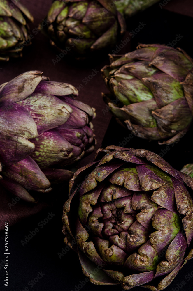 Obraz premium fresh purple artichokes on black background