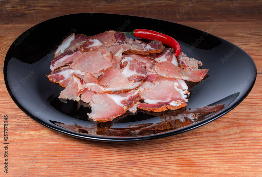 Thin slices of dried pork and chili on black dish Thin slices of dried pork and chili on black dish