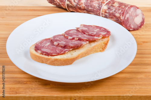 Open sandwich with dry-cured sausage and not sliced sausage