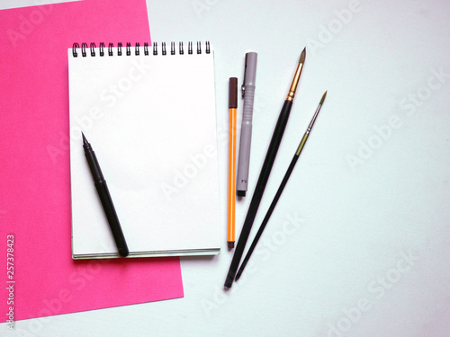 Art table colorful sheets of paper and blank notebook on white background