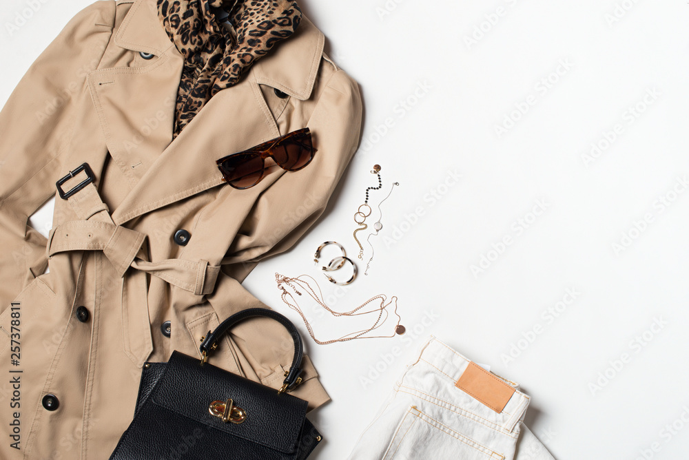 Women fashion clothes and accessories flat lay, beige trench coat with bag, glasses, denim and western boots