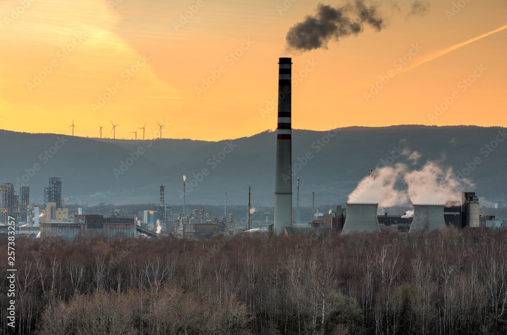Heavy industry, petrochemical factory with wind power turbines on the hill. Environmental pollution versus renewable energy resource . Heavy industry, petrochemical factory with wind power turbines on the hill. Environmental pollution versus renewable energy resource .