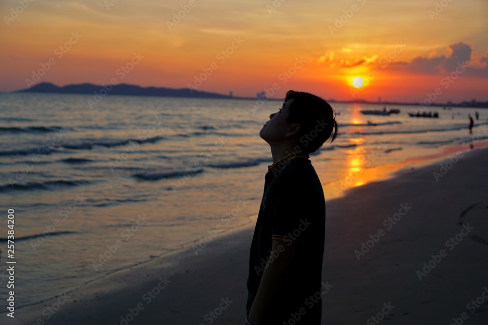 Silhouette of young man looking up sky having sunset beach in summer vacation as twilight times at Pattaya,Thailand., Many tourists visit here, View for seascape, Travel concept, Space for text