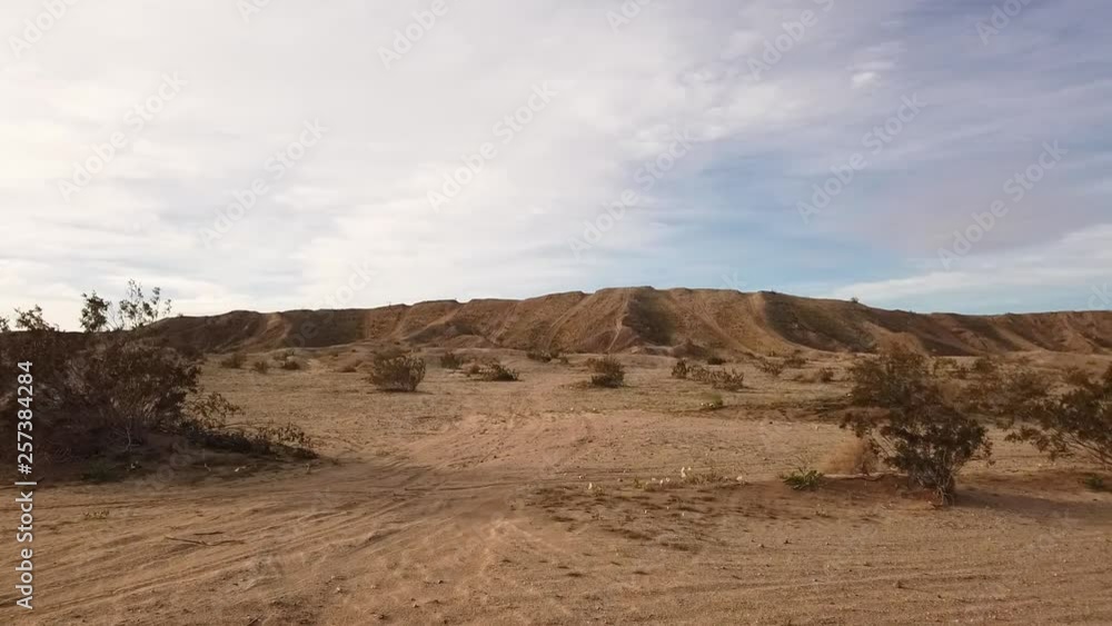 Panning view of sandy surface marked with off road vehicle tire tracks and rising hills beyond Panning view of sandy surface marked with off road vehicle tire tracks and rising hills beyond