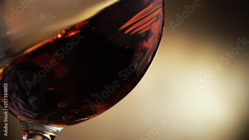 Cognac is rotated in a glass. On dark background.