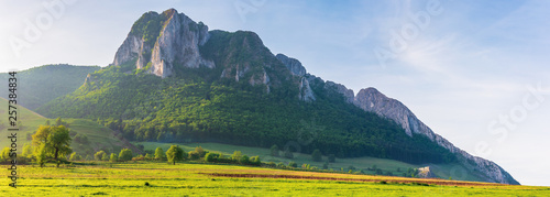 beautiful panorama of romania countryside. wonderful sunny morning in mountains. grassy meadow on the hillside and Piatra Secuiului