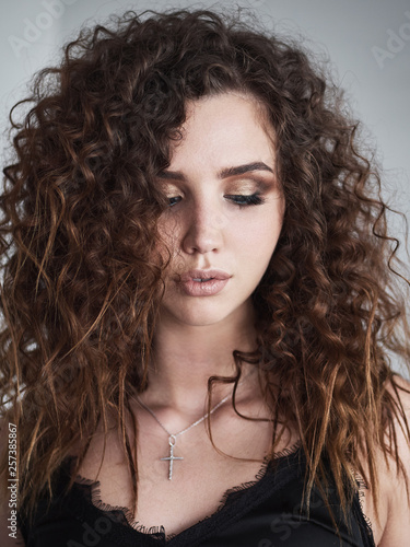 Close up lifestyle portrait of young beautiful red head woman with trendy curly hairstyle, blue eyes, professional makeup
