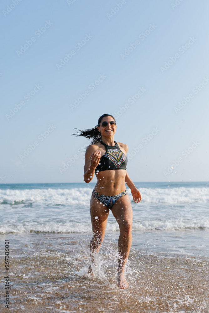 Fit young woman in bikini running at the beach into the sea splashing water  drops. Outdoor fitness, healthy lifestyle and summer freedom concept. Stock  Photo | Adobe Stock
