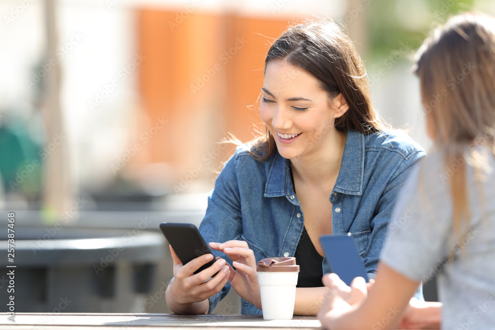 Happy woman checking smart phone messages in a park