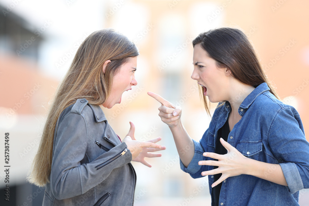 Two women fighting shouting each other in the street