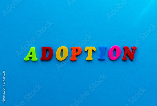 text adoption from plastic colored letters on blue paper background