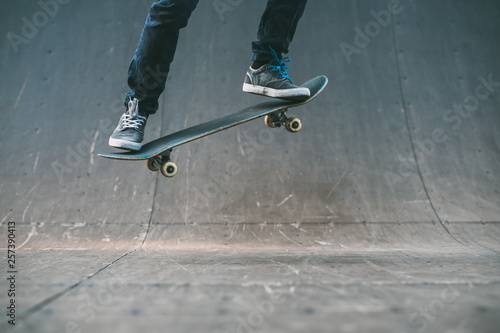 Skateboarder in action. Extreme sports lifestyle. Hipster feet performing ollie trick. Cropped shot. Copy space.
