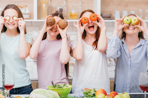 Dieting together. Healthy nutrition. Organic cooking. Excited young females posing with foods covering eyes.