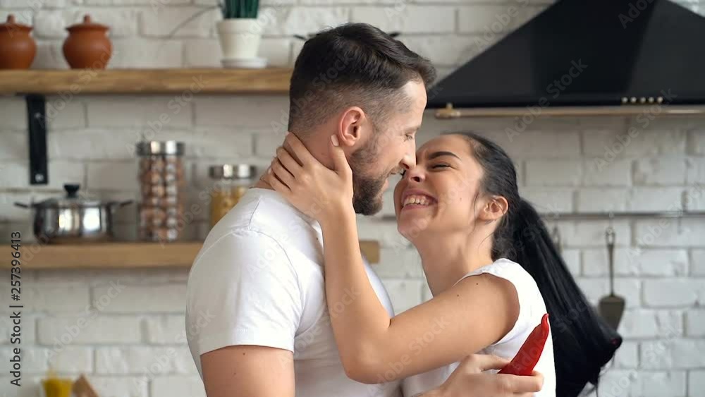 Portrait of happy young couple at the kitchen. Cooking, singing, having fun and kissing. Portrait of happy young couple at the kitchen. Cooking, singing, having fun and kissing.