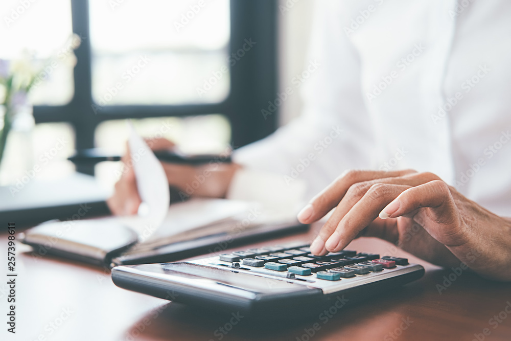 Woman with bills and calculator. Woman using calculator to calculate bills at the table in office. Calculation of costs. Woman with bills and calculator. Woman using calculator to calculate bills at the table in office. Calculation of costs.