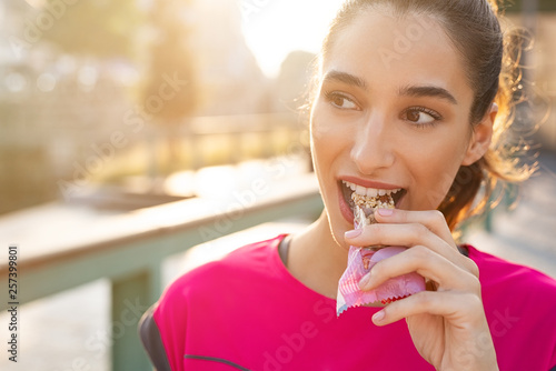 Sporty woman eating energy bar Poster Mural XXL