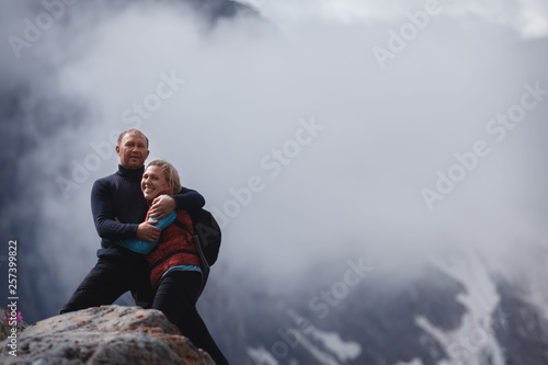 Romantic young happy couple kissing and hugging. rain and fog. Young couple in love on the background of mountains