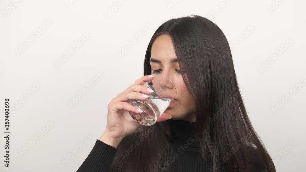 Young woman drinking a glass of water. Isolated, on blurred background Young woman drinking a glass of water. Isolated, on blurred background