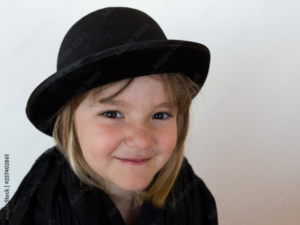 Closeup of cute smiling little girl wearing a black bowler hat and shawl Closeup of cute smiling little girl wearing a black bowler hat and shawl