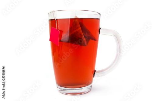Red tea glass cup with tea bag isolated on white background. Fruit tea with triangle tea bag in cup. 