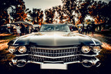 Close-up wide-angled photo of black vintage retro car with shining chrome radiator grille, bumper and headlamps