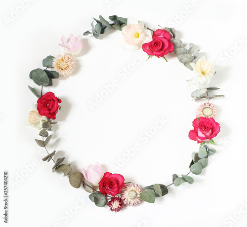 Spring, Easter feminine styled scene, floral composition. Round frame wreath made of pink roses, tulips, daffodils, everlasting flowers and eucalyptus branches. White background. Flat lay, top view.