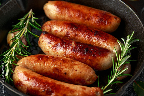 Freshly cooked butchers made, homemade sausages with rosemary in cast iron frying pan