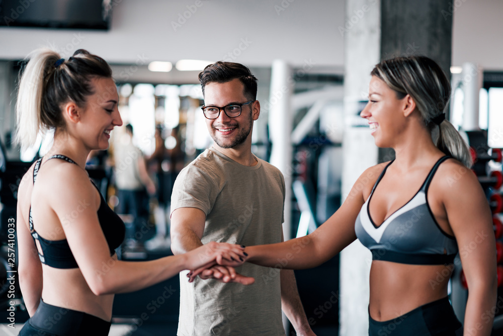 Fototapeta premium Young fit sports people putting hands together in the gym.