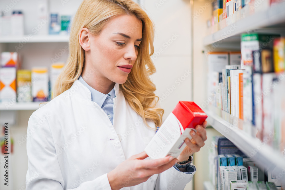 Pharmacist looking at medication in modern pharmacy.