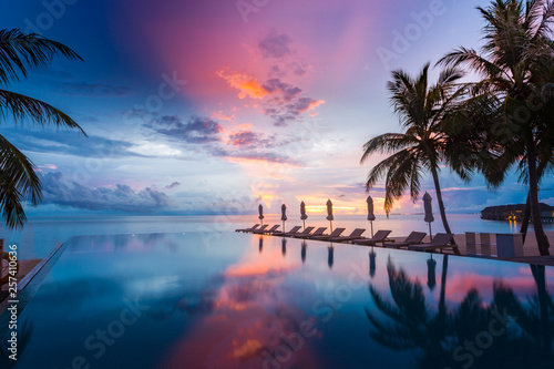 Beautiful poolside and sunset sky. Luxurious tropical beach landscape, deck chairs and loungers and water reflection
