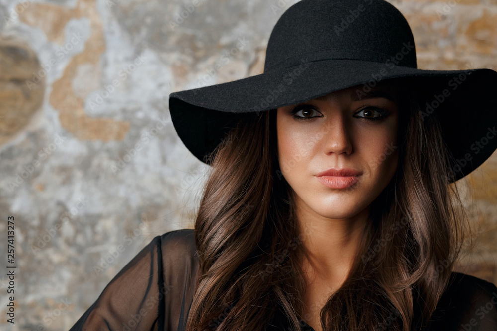 Fashionable model wearing hat and blouse posing in the dark. Space for text Fashionable model wearing hat and blouse posing in the dark. Space for text