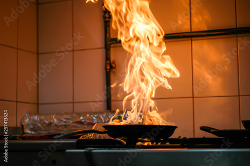 The chef cooking and makes a fire in a pan. Cooking with fire. Crown food. Charismatic chef in the kitchen.