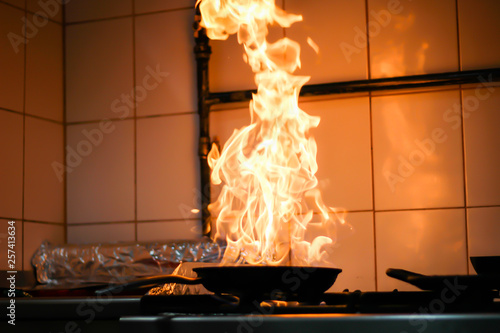 The chef cooking and makes a fire in a pan. Cooking with fire. Crown food. Charismatic chef in the kitchen.