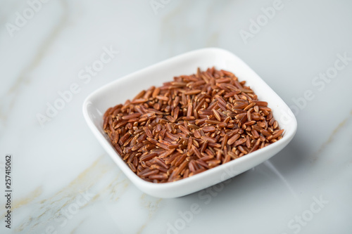 Rotschaliger roher Roter Jasmin Reis in Porzellan Schale auf Marmor Hintergrund und ist eine Spezialität aus Kambodscha Asien