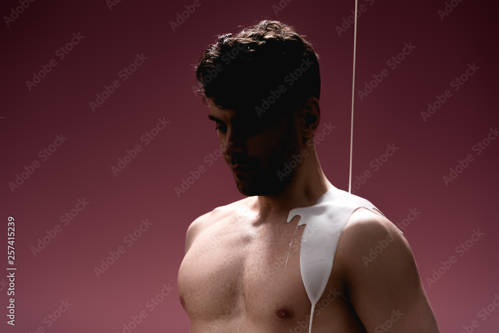 Fototapeta premium confident man with white paint spills on body on purple