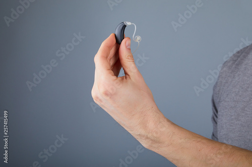 Photos Man holding hearing aid, closeup